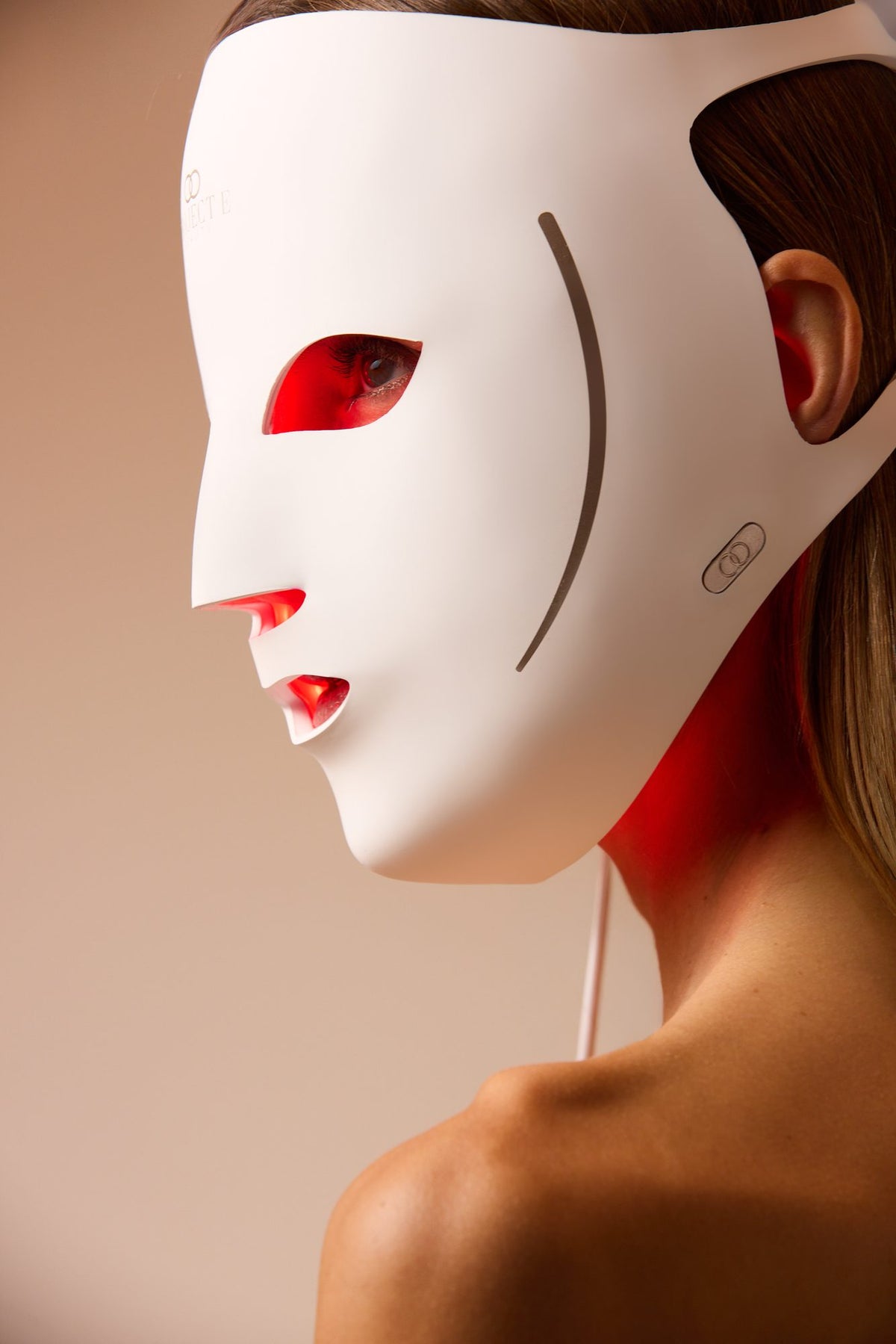 Side profile of a woman wearing the LumaLux Face V2 LED mask showing the control button